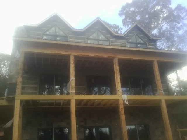 Dormers and porch framing on a large log home under construction — Roof Coating work by our crew in Manson