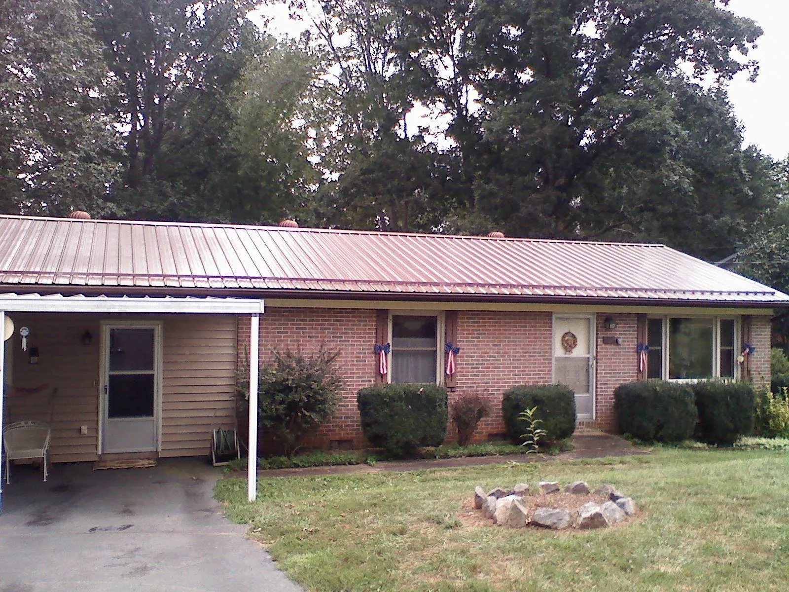 Bronze metal roof and carport on a brick ranch home — Roof Repair work by our crew in Manson